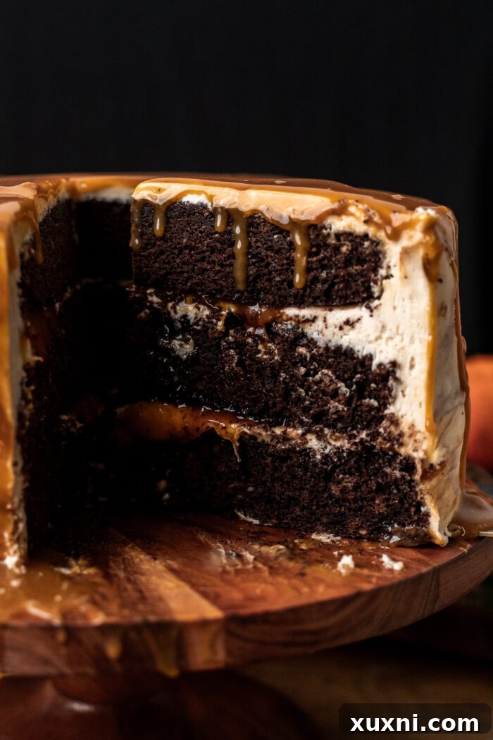 Close-up of a slice of vegan butterbeer cake, revealing moist chocolate layers, butterscotch filling, and creamy frosting.