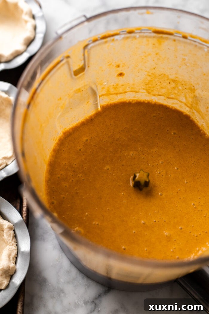 Smooth, perfectly blended vegan pumpkin pie filling in a food processor, showcasing its creamy consistency.