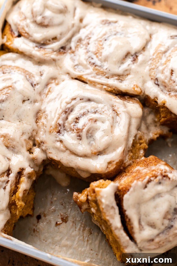 Gluten-free pumpkin cinnamon rolls perfectly arranged in a baking dish, showcasing their golden tops and tempting spiral layers, ready to be enjoyed.