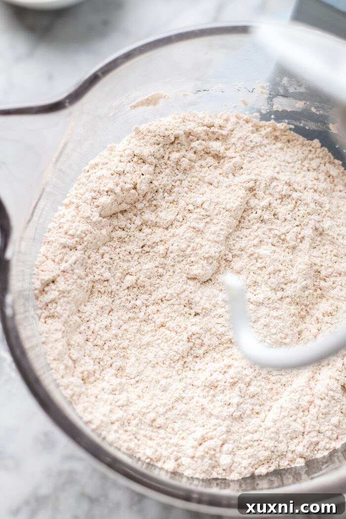 Dry gluten-free flours and spices, perfectly whisked together in a stand mixer bowl, ready for the wet ingredients to be added.