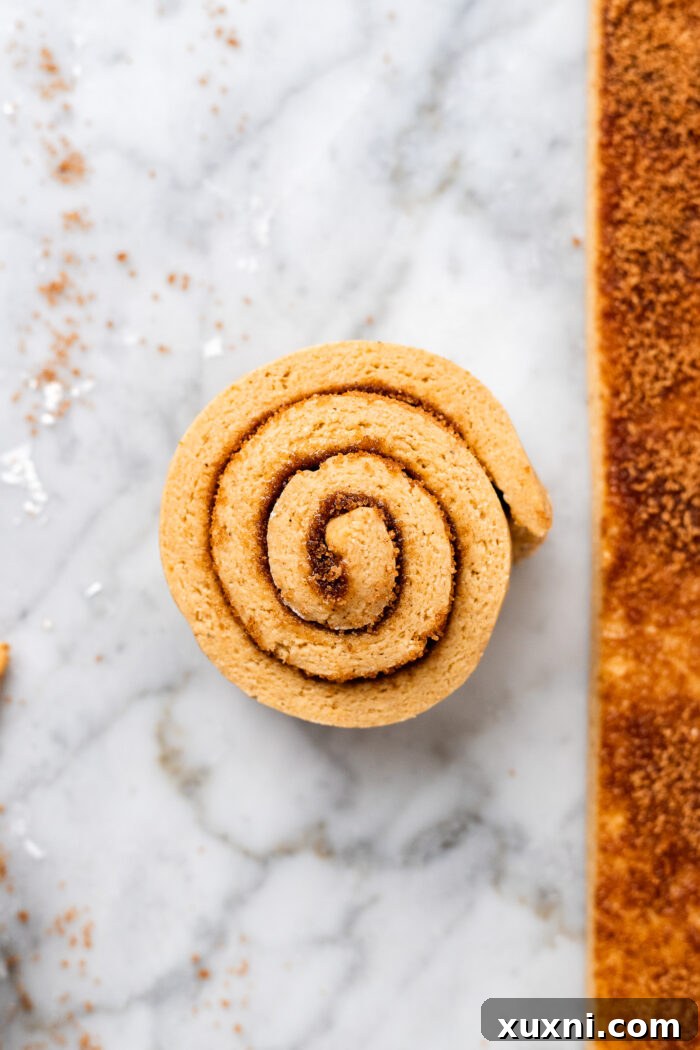 Neatly rolled pumpkin cinnamon roll spirals, freshly sliced with a pizza cutter, showcasing their classic swirl pattern on a marble countertop.