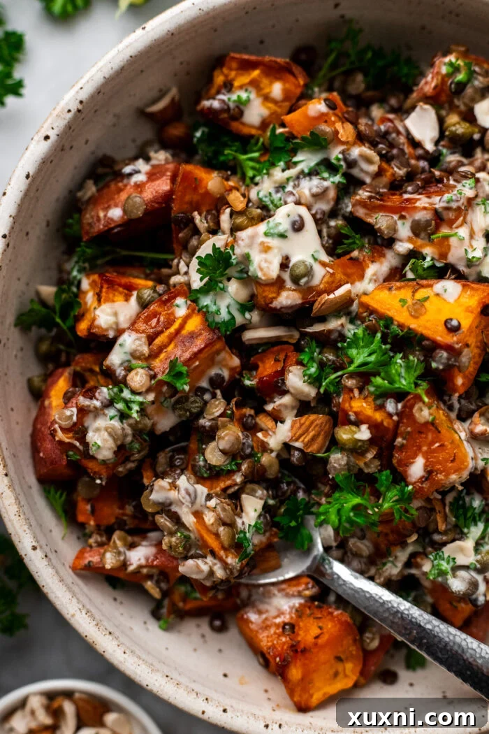 Scooping up a generous portion of the warm roasted lentil sweet potato salad into a bowl