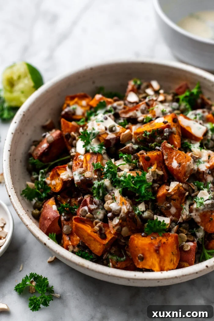 Roasted lentil sweet potato salad in a bowl with a freshly squeezed lime wedge, highlighting its fresh ingredients