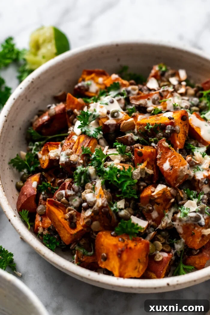 Close-up of a warm roasted lentil sweet potato salad, showing rich textures and colors