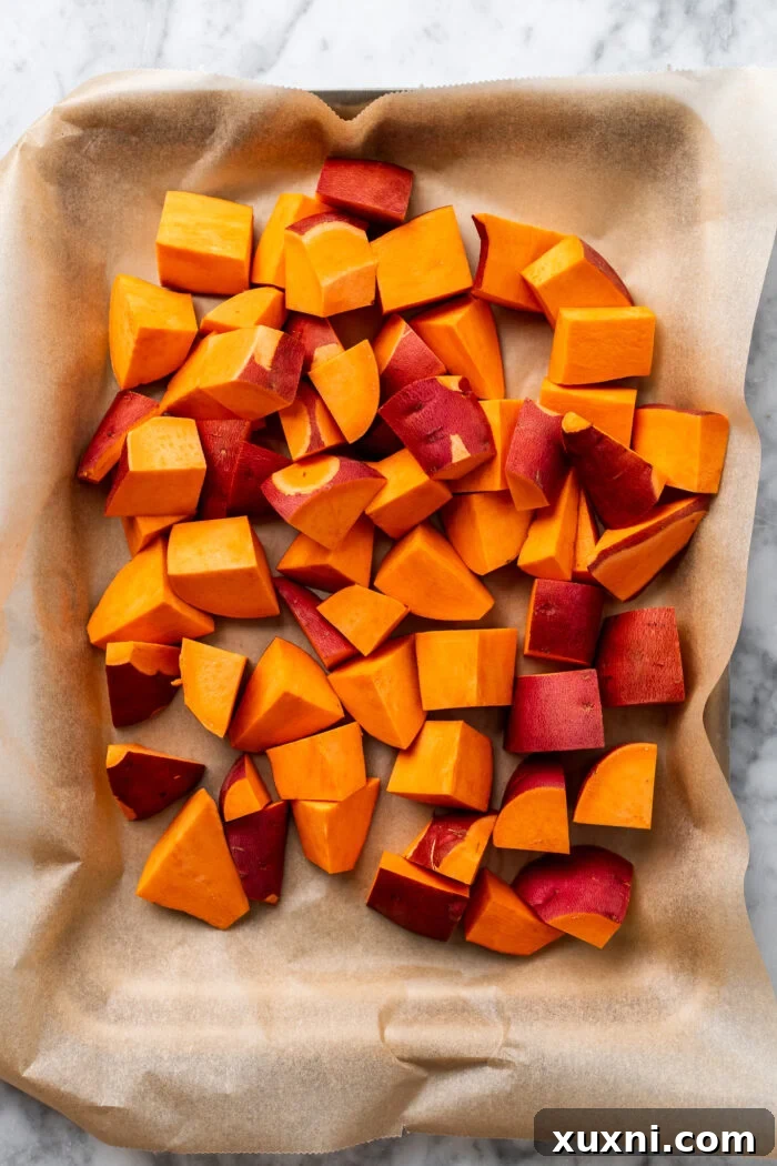 Sliced sweet potato wedges arranged on a parchment-lined baking sheet