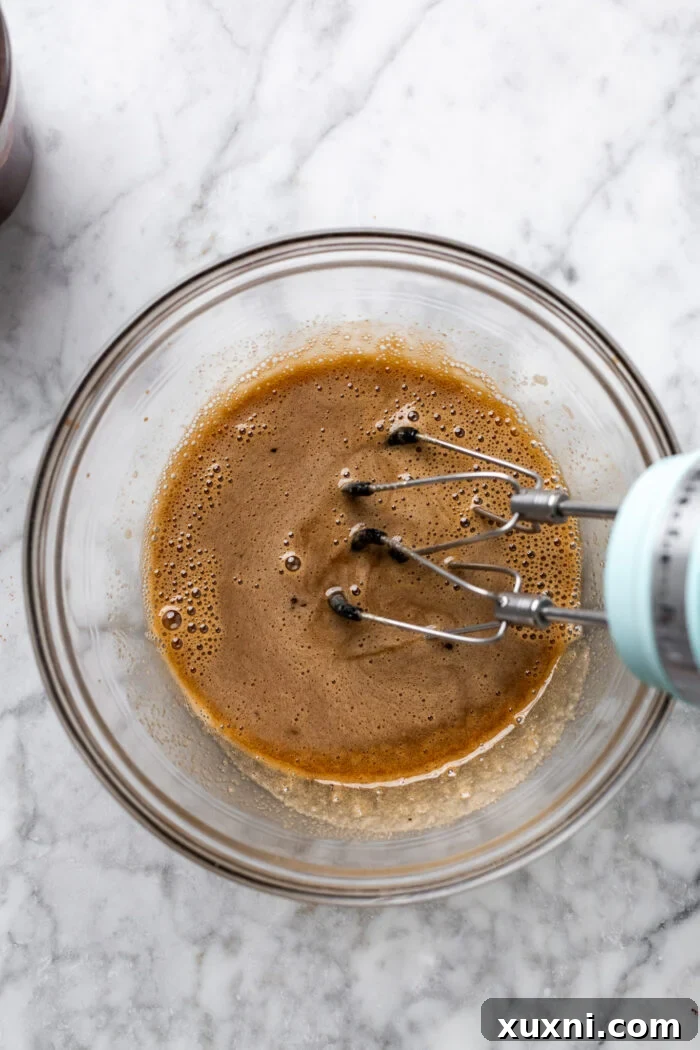 Effortless Fudgy Vegan Brownie Cookies 6 Mixing aquafaba with sugar in a bowl to create the base batter
