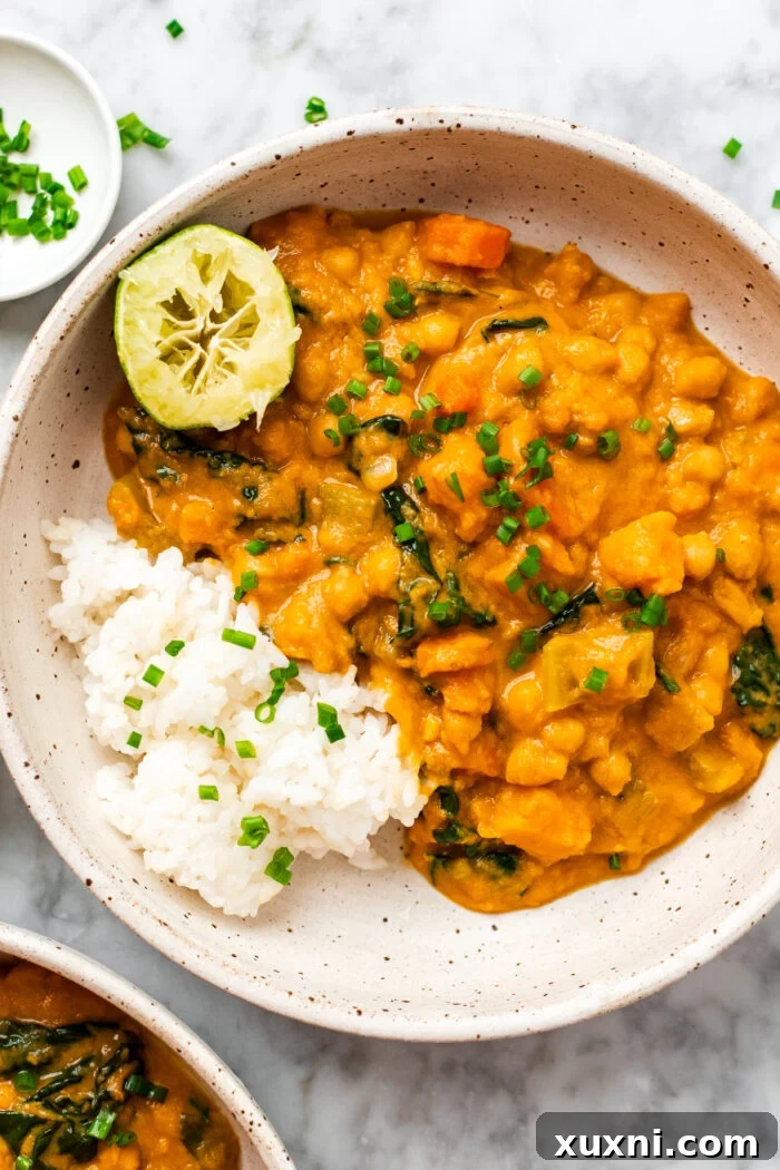Creamy Peanut Butter Sweet Potato Curry with Chickpeas and Kale 2 A vibrant bowl of sweet potato curry garnished with fresh lime wedge and herbs, ready to be enjoyed.