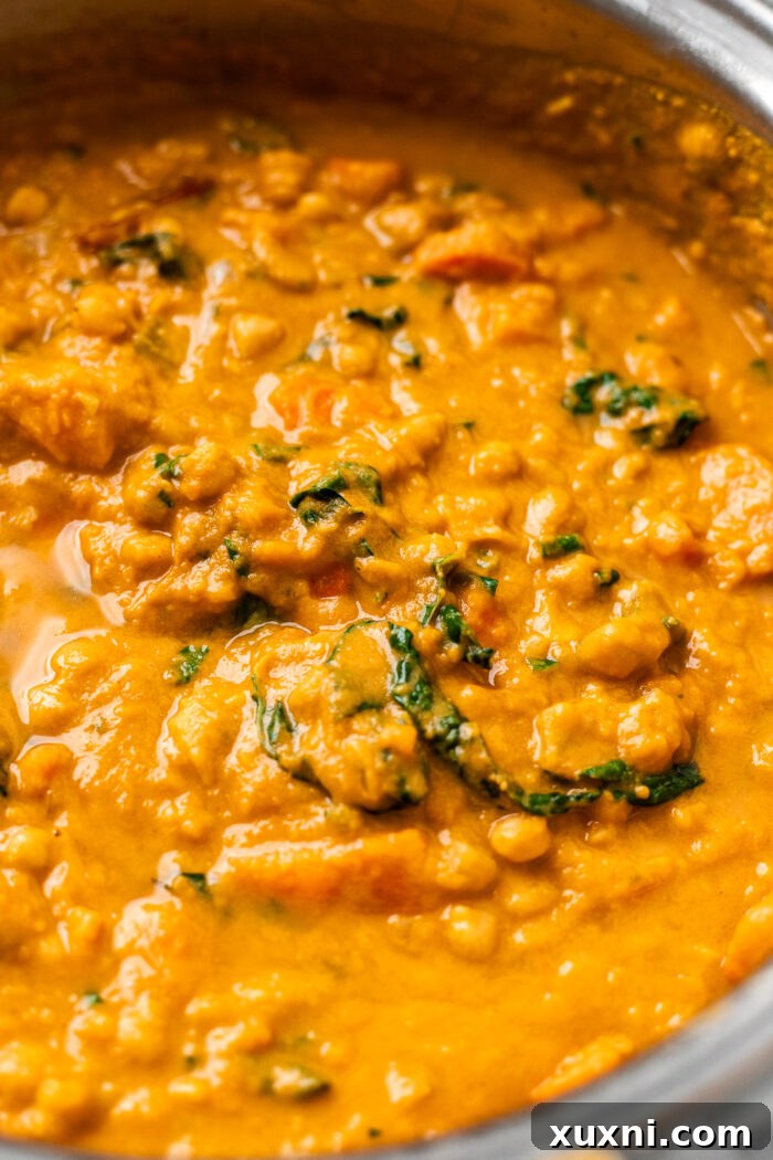 Creamy Peanut Butter Sweet Potato Curry with Chickpeas and Kale 4 A large pot filled with the bubbling sweet potato curry, rich with color and texture, ready to finish cooking.