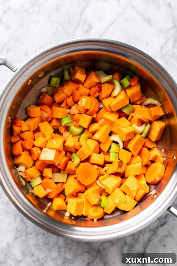 Creamy Peanut Butter Sweet Potato Curry with Chickpeas and Kale 7 Adding chopped carrots, celery, and sweet potatoes to the pot with sautéed aromatics, then gently cooking them.