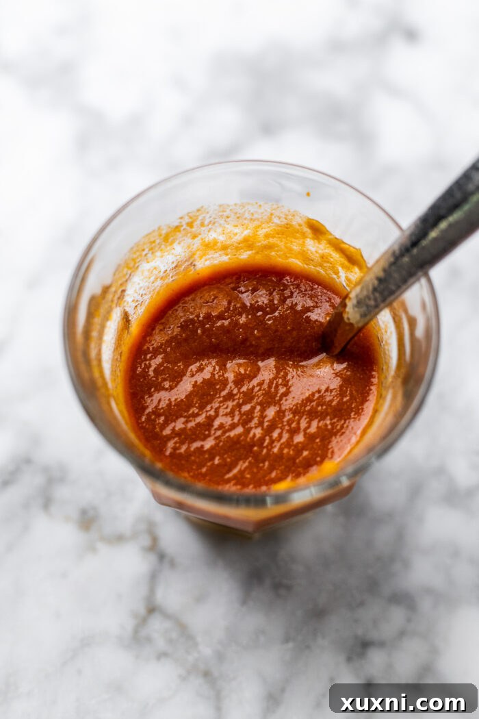 Creamy Peanut Butter Sweet Potato Curry with Chickpeas and Kale 8 A small bowl containing a creamy mixture of red curry paste and peanut butter, ready to be added to the curry.