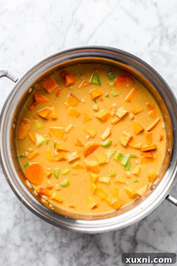 Creamy Peanut Butter Sweet Potato Curry with Chickpeas and Kale 9 All the main ingredients, including chickpeas, coconut milk, and the curry paste mixture, combined in the pot before simmering.