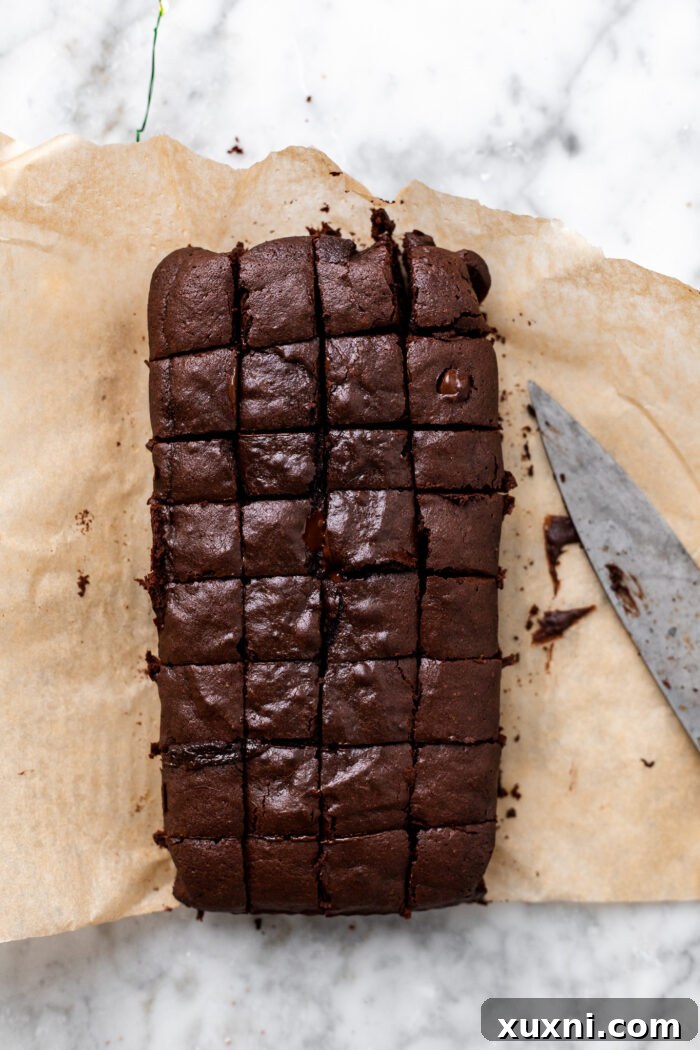 Baked brownie loaf being sliced into small squares.
