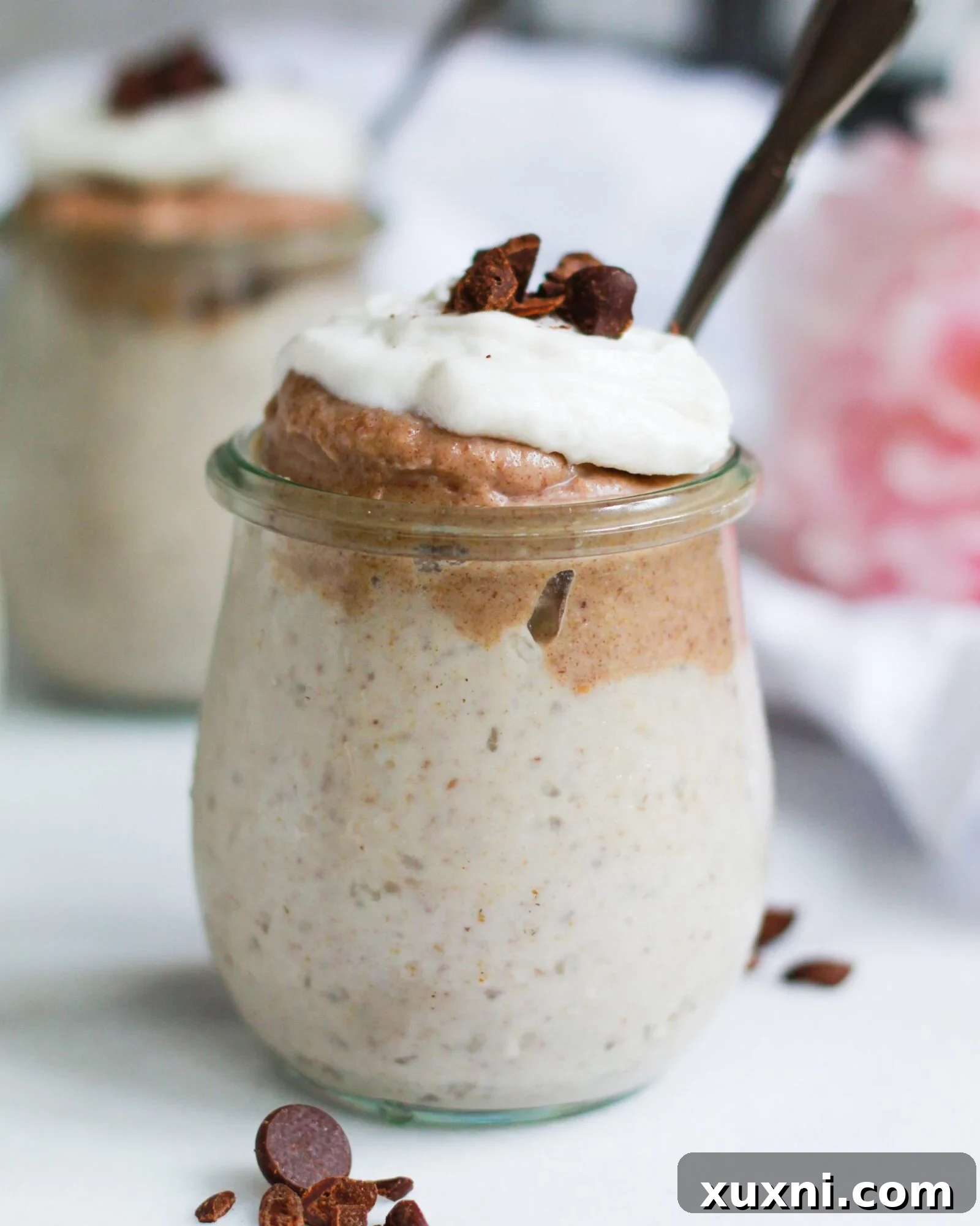 A jar of luxurious homemade vegan butterscotch pudding topped generously with fluffy coconut whipped cream, ready to be enjoyed.