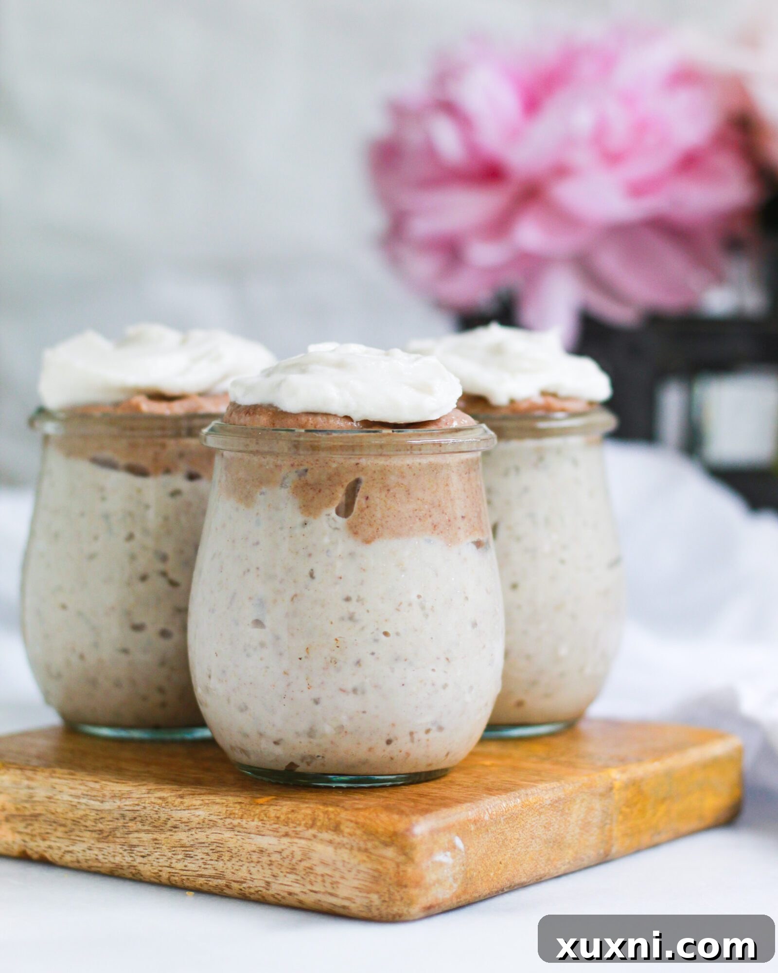 Three jars of sumptuous butterscotch pudding, beautifully garnished with swirls of salted caramel sauce and a dollop of whipped cream.