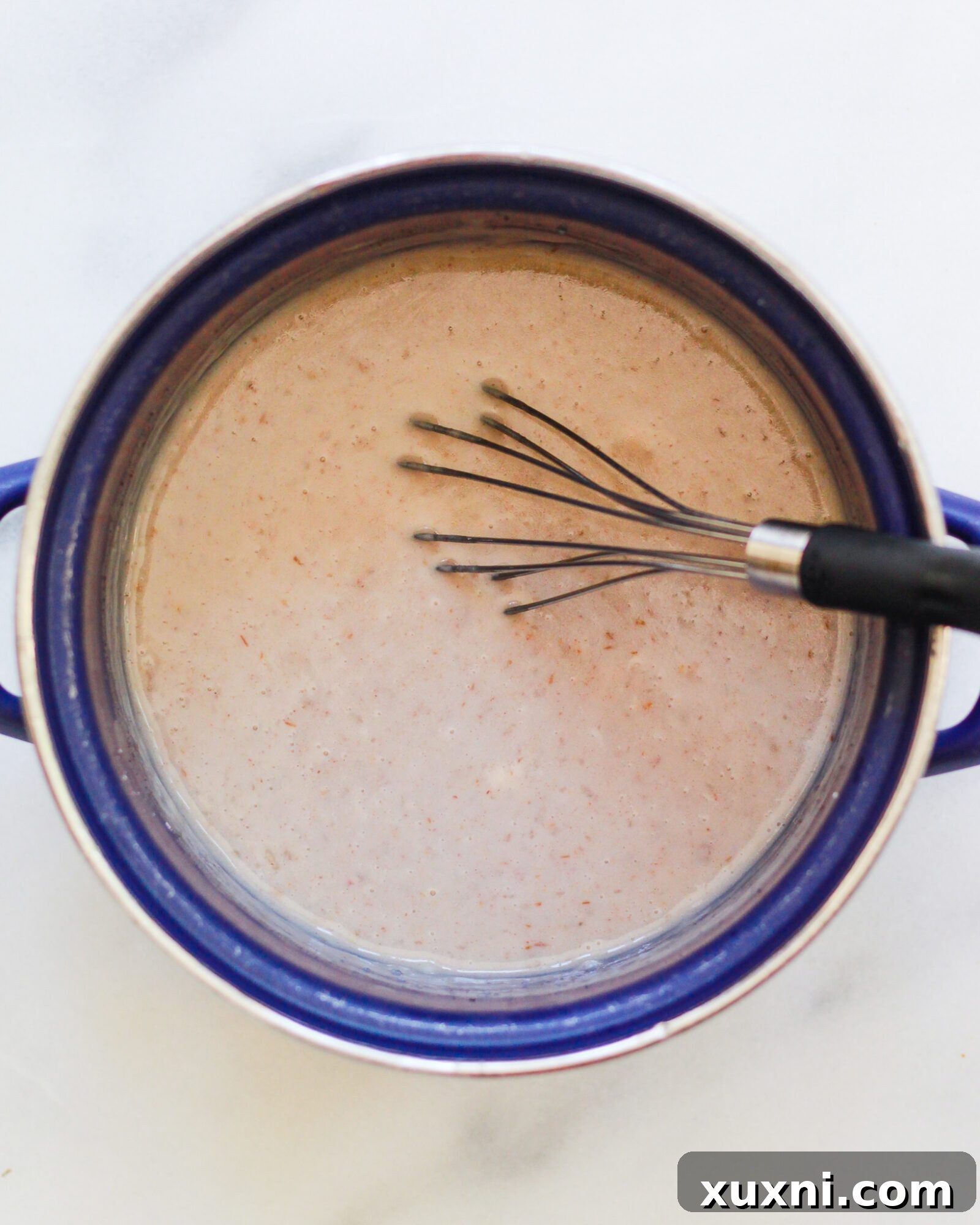 A saucepan filled with the golden mixture for homemade butterscotch pudding, simmering gently on the stovetop.