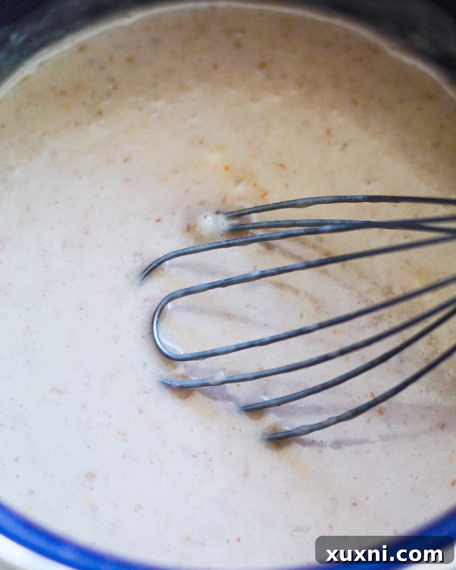 A close-up view of homemade vegan butterscotch pudding simmering on the stove, showing its thickening process and creamy texture.