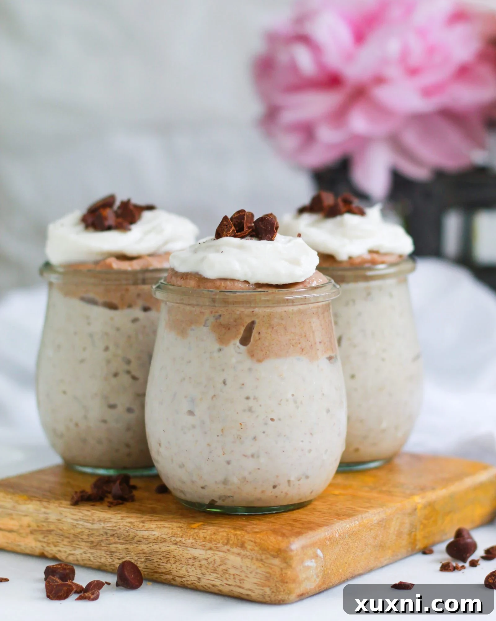 Three elegant jars of classic vegan butterscotch pudding, generously garnished with dark chocolate chips for an added layer of flavor and texture.