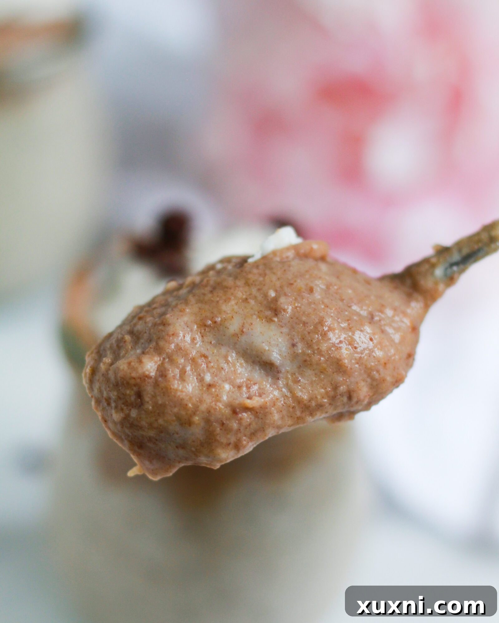 A delightful close-up of a spoon scooping a generous portion of creamy vegan butterscotch pudding, showcasing its perfect consistency.
