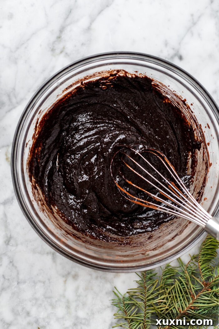 Wet ingredients for chocolate blossoms being whisked in a bowl with cocoa powder.