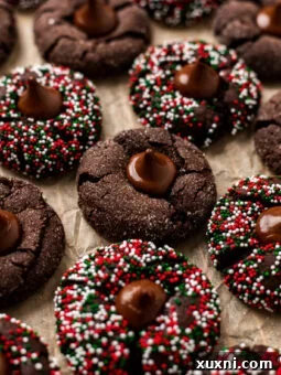 Perfectly baked vegan chocolate blossoms on parchment paper, topped with homemade chocolate kisses and festive sprinkles.