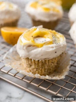 A freshly baked vegan lemon cupcake, adorned with a swirl of cream cheese frosting and a dollop of bright lemon curd, ready to be enjoyed.