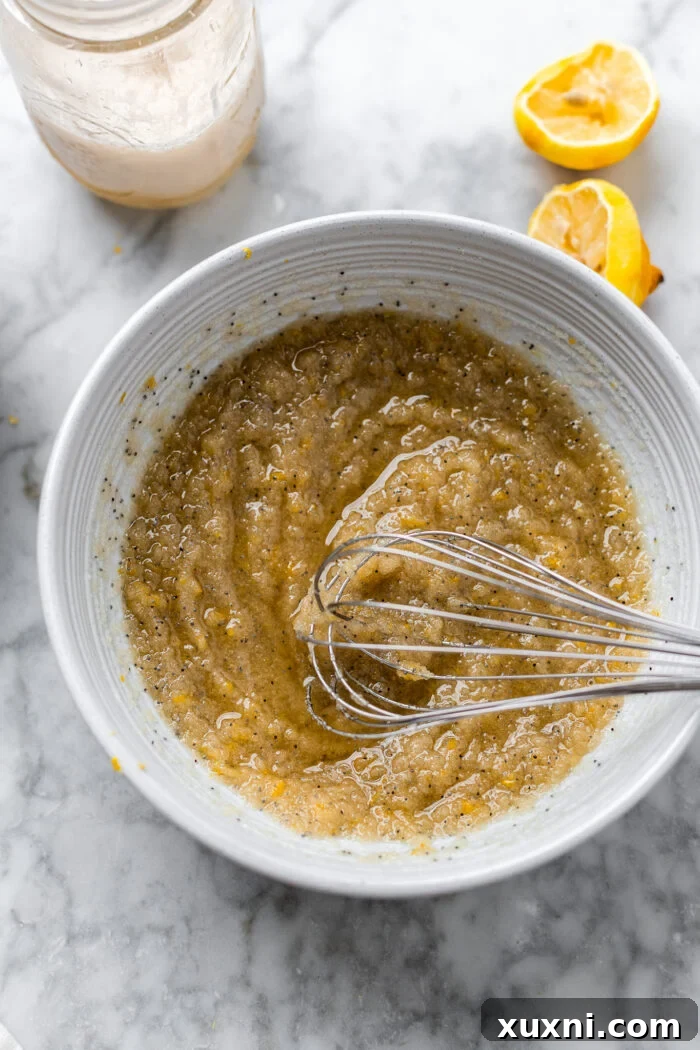 Whisked vegan lemon cupcake batter in a glass bowl, showcasing a smooth, creamy texture and light yellow hue from the lemon zest.