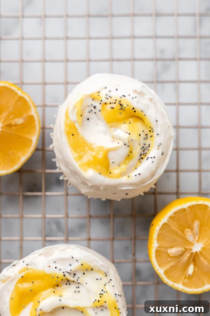 Beautifully frosted vegan lemon poppy seed cupcakes, adorned with a swirl of cream cheese frosting and a dollop of lemon curd, ready to be served.