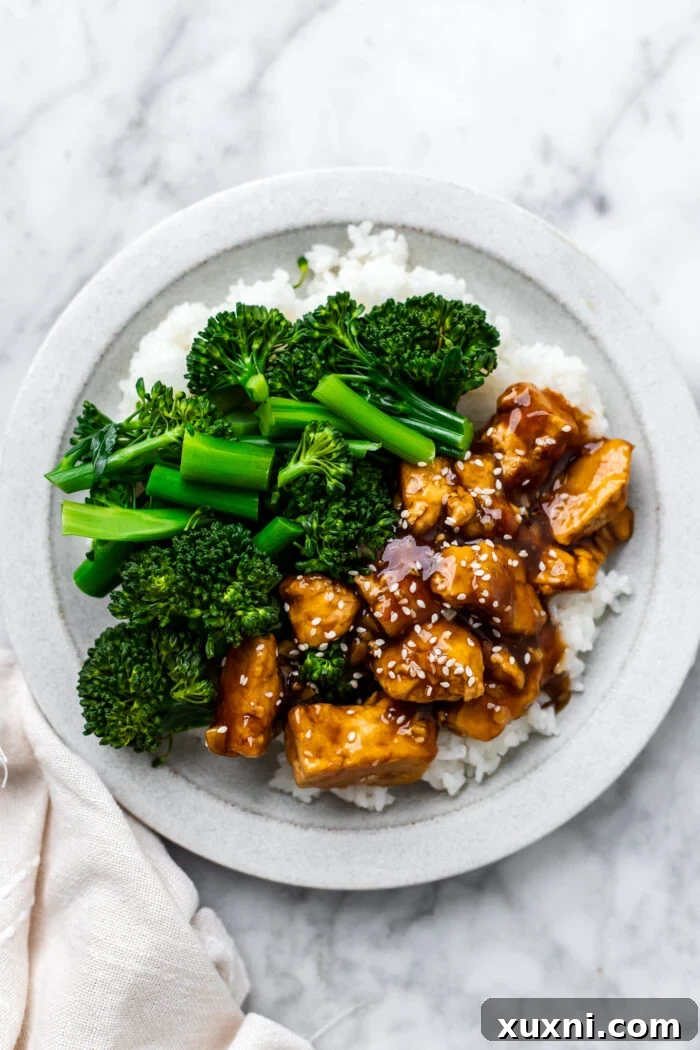 plate of teriyaki tofu with broccoli and rice on a blue plate with a cloth