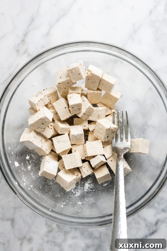 tofu being coated in arrowroot starch, ready for cooking