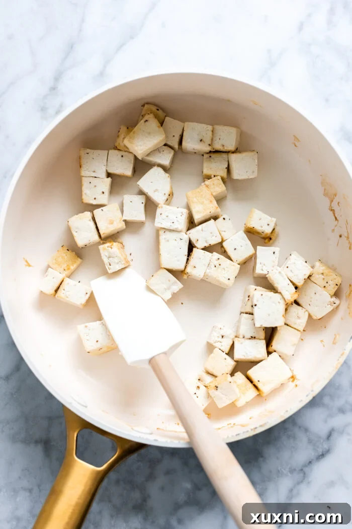 crispy tofu searing in a pan with vegan butter