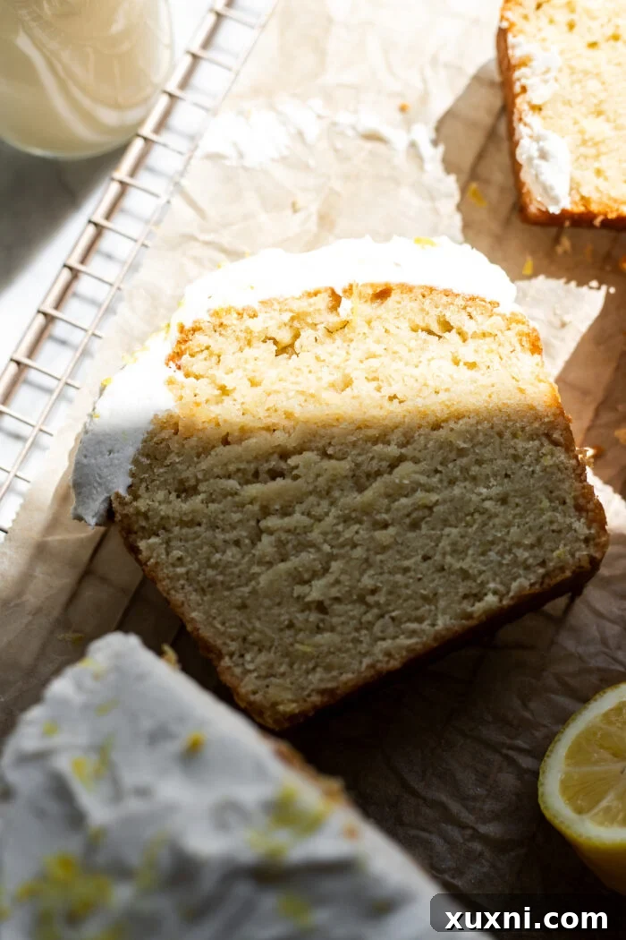 A slice of vegan lemon drizzle cake resting on parchment paper, highlighting its tender texture.