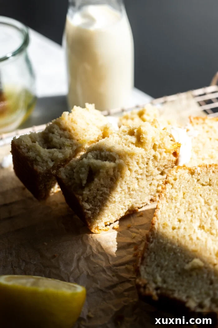 A slice of vegan lemon drizzle cake cut in half, showcasing its interior crumb and moistness.