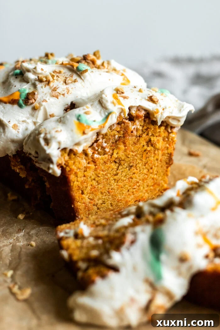 Close-up of a sliced carrot loaf, showing the vibrant specks of finely shredded carrots throughout the cake.