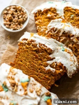A slice of vegan carrot cake loaf with cream cheese frosting.