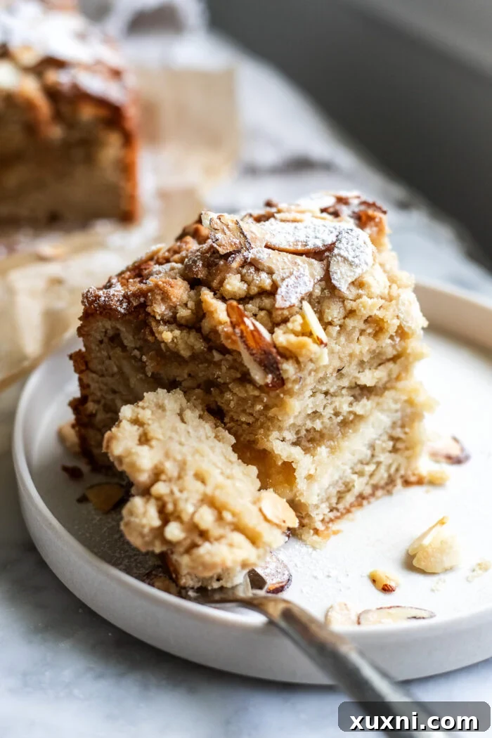 A slice of vegan almond coffee cake with a bite taken out, showing the layers.