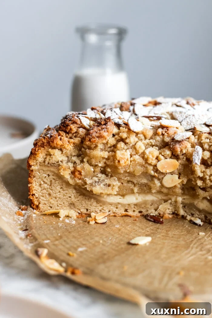 Close-up of a generously sliced vegan almond coffee cake on parchment paper, revealing its moist layers.