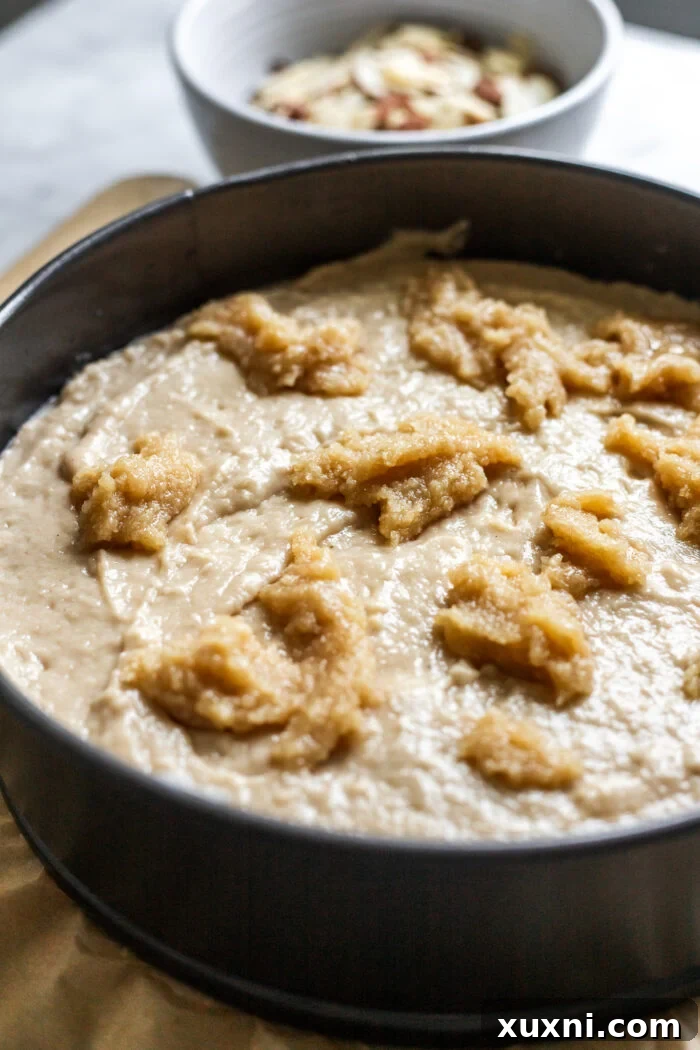 Final layers of vegan almond coffee cake being added to the pan before baking.