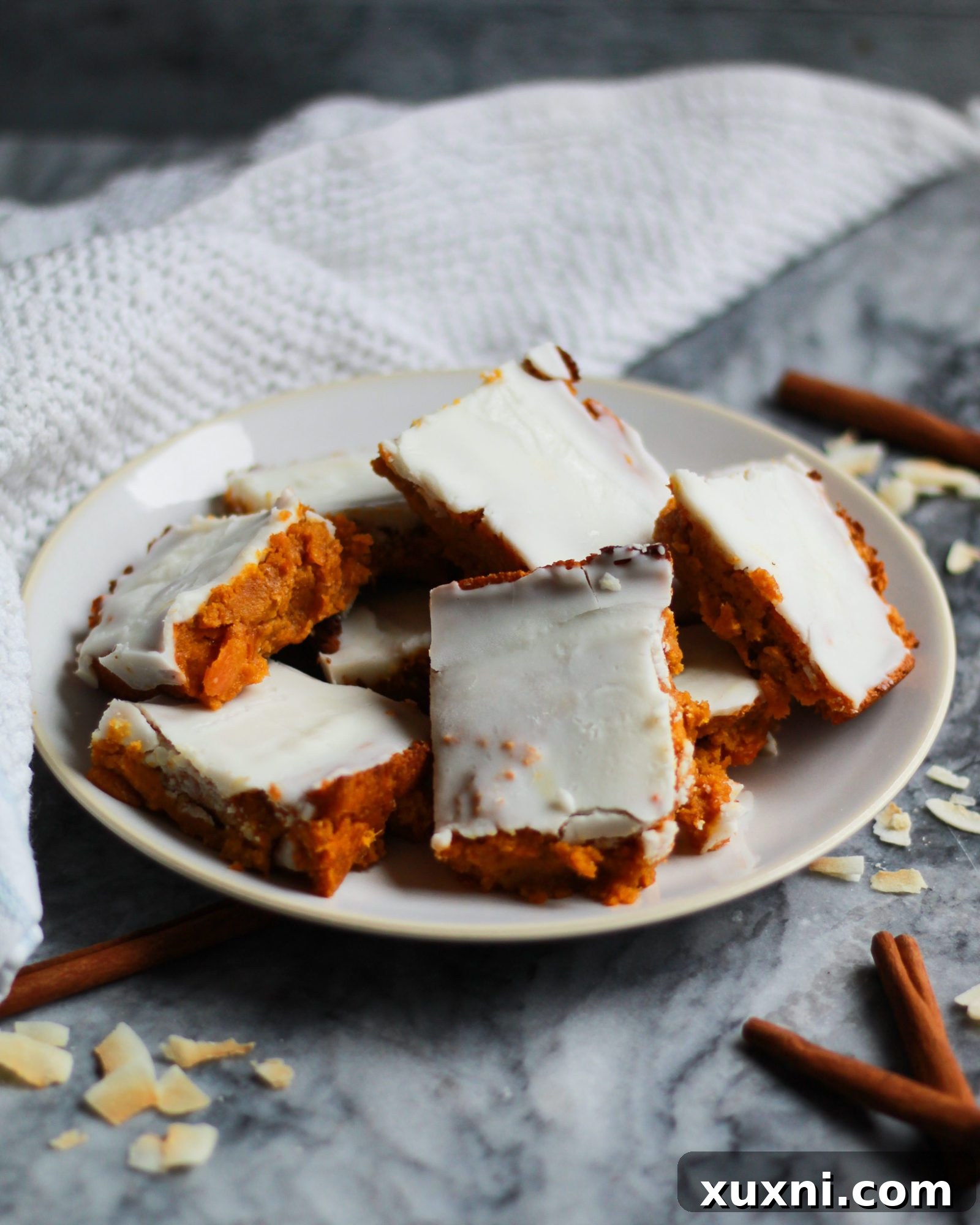 Side view of a plate of delectable carrot cake bars, perfectly frosted.