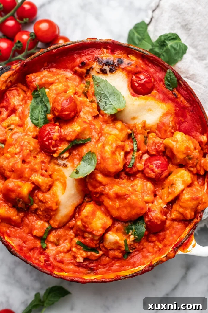 A baking dish filled with assembled Gnocchi alla Sorrentina, topped with melted vegan mozzarella, ready for the oven.