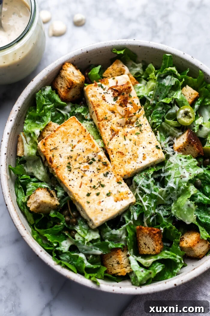 Super Simple Vegan Caesar with Zesty Lemon Tofu 3 Close-up view of a generously dressed Vegan Caesar salad, highlighting the creamy texture of the dressing and the freshness of the ingredients.