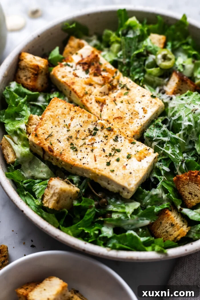 Super Simple Vegan Caesar with Zesty Lemon Tofu 8 A generously portioned vegan salad in a bowl, featuring crisp greens and savory tofu pieces.