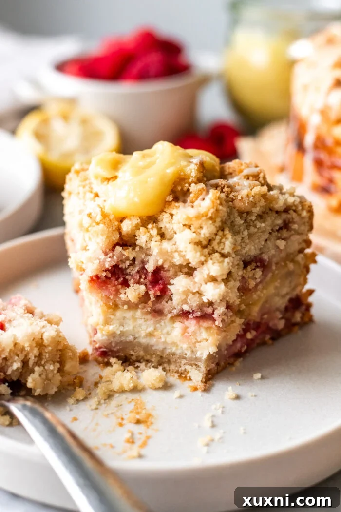 Irresistibly Soft Vegan Lemon Raspberry Coffee Cake with a Zesty Vegan Cream Cheese Swirl 2 A perfectly sliced piece of vegan lemon raspberry coffee cake with a bite taken out, revealing the creamy lemon swirl and fresh raspberries.