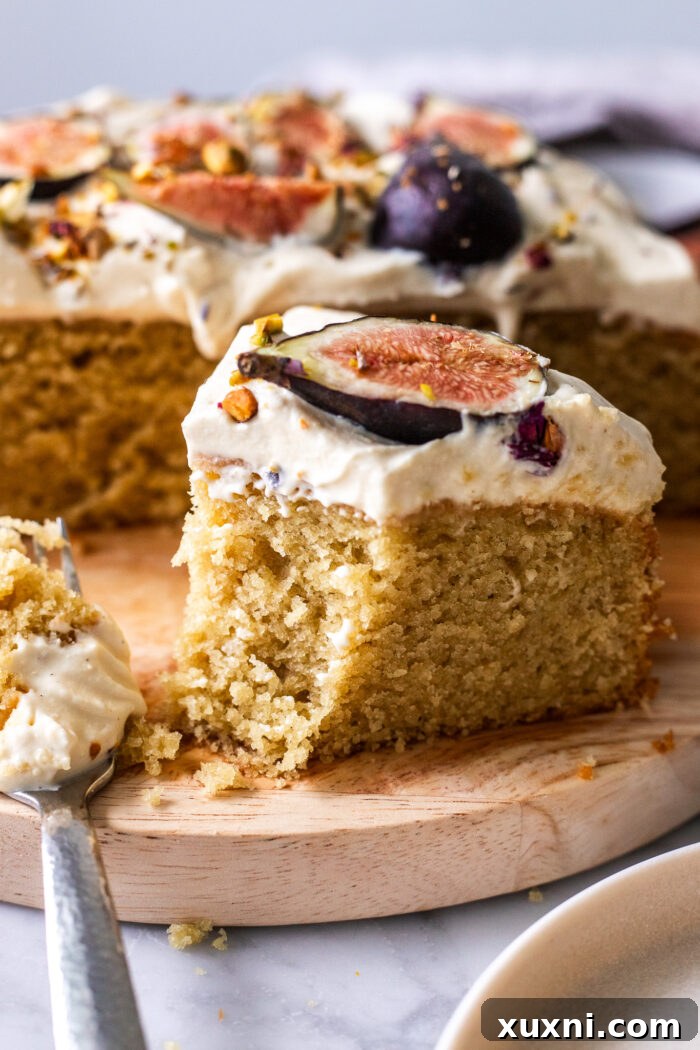 A close-up of a bite-sized piece of vegan olive oil cake on a fork, showing its moist texture and creamy frosting.
