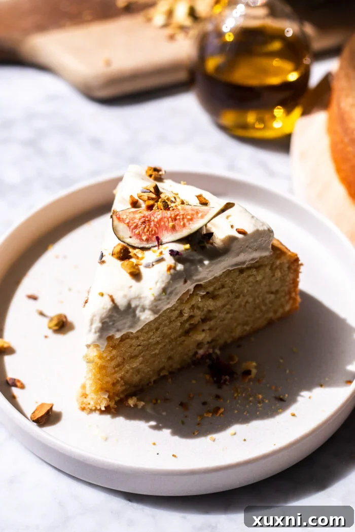 A pristine slice of vegan olive oil cake, perfectly plated with a generous dollop of dairy-free mascarpone cream, ready to be enjoyed.