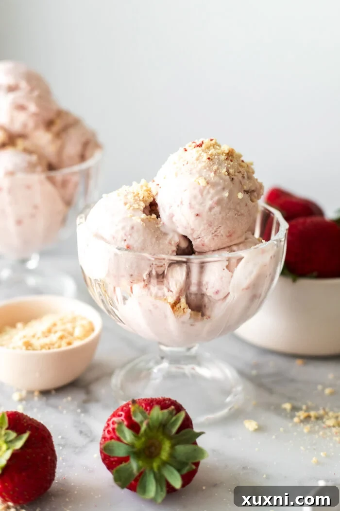 Scooped creamy vegan strawberry ice cream in a bowl, garnished with fresh strawberries