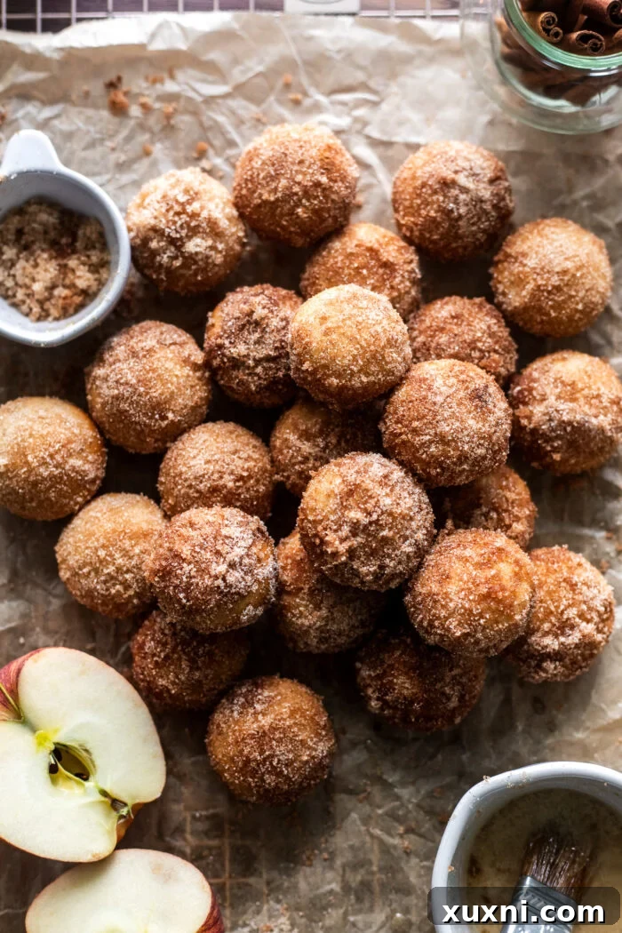 Freshly baked vegan apple cider donut holes cooling on a wire rack, glistening with cinnamon sugar.
