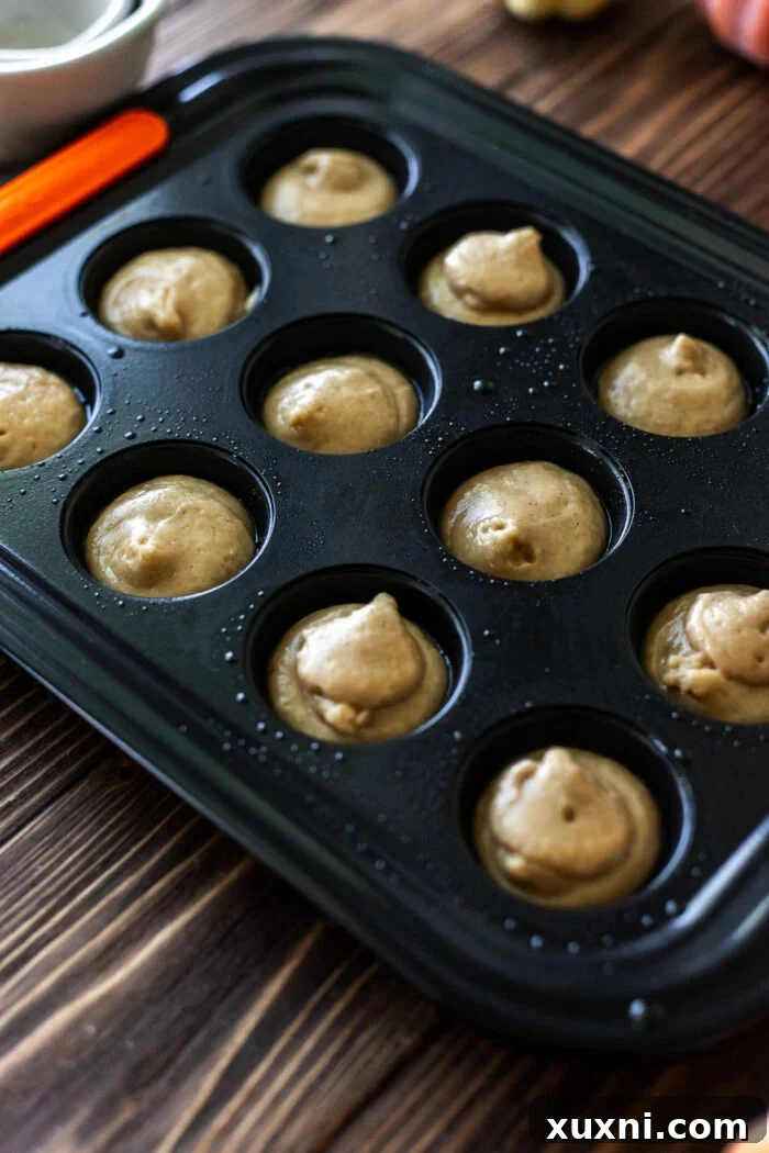 Donut hole batter piped into a mini muffin pan, ready for baking.