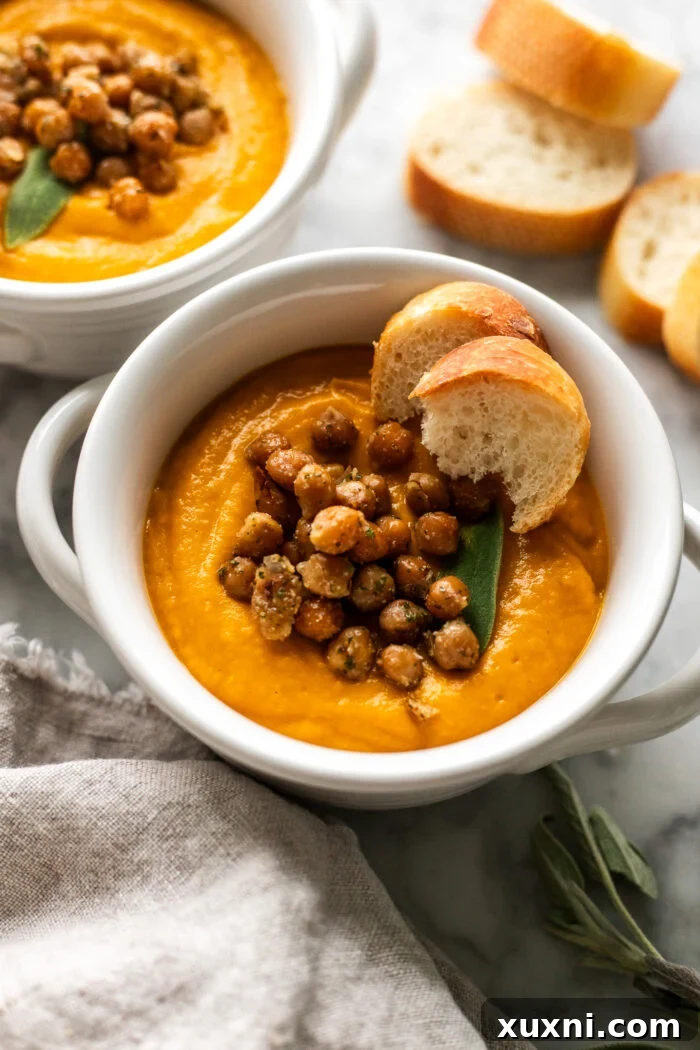 A beautiful bowl of creamy vegan pumpkin soup, garnished with fresh herbs and a drizzle of olive oil, ready to be enjoyed.