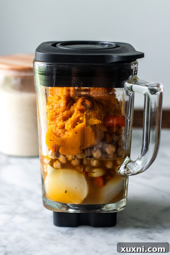 A blender jar filled with perfectly roasted vegetables and cooked chickpeas, ready to be transformed into creamy soup.