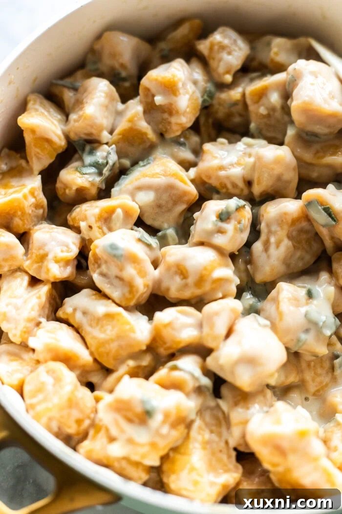 Freshly cooked vegan pumpkin gnocchi in a sauté pan, glistening with brown butter garlic sage sauce.